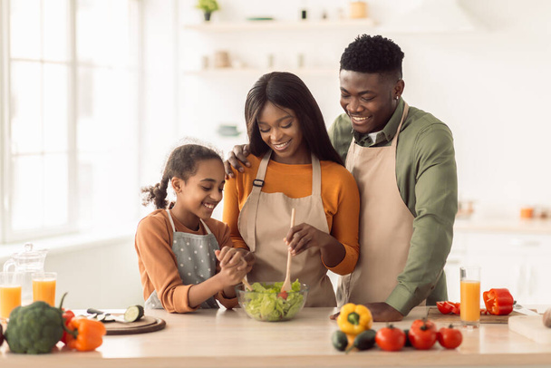 Чорна родина готує салат готуючи вечерю на кухні
 - Фото, зображення