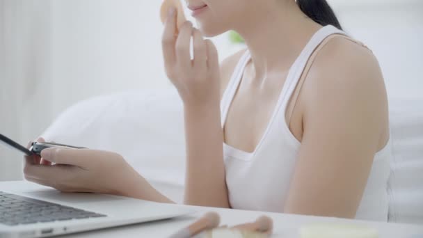 Manos de mujer con maquillaje de aprendizaje con soplo de polvo en la mejilla viendo ordenador portátil con curso de tutorial en línea, la enseñanza femenina y explicar maquillaje con cosméticos en las redes sociales streaming. - Imágenes, Vídeo