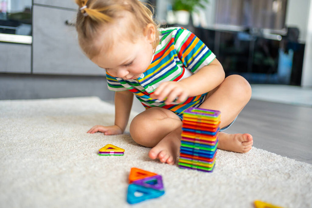 Little girl playing colorful magnet plastic blocks kit at home. The child playing educational games. Early childhood development. - Foto, imagen