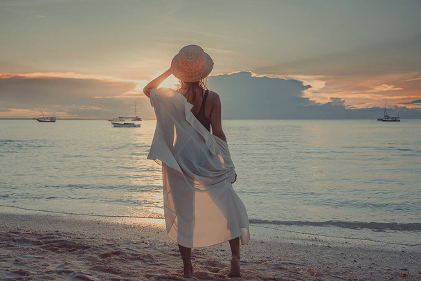 Woman stand on a beach in front of ocean on a scenic sunset. Zanzibar, Tanzania - Foto, afbeelding