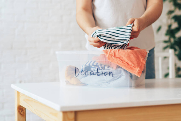 Chica pone ropa usada en recipiente de plástico con la donación de inscripción - Foto, imagen