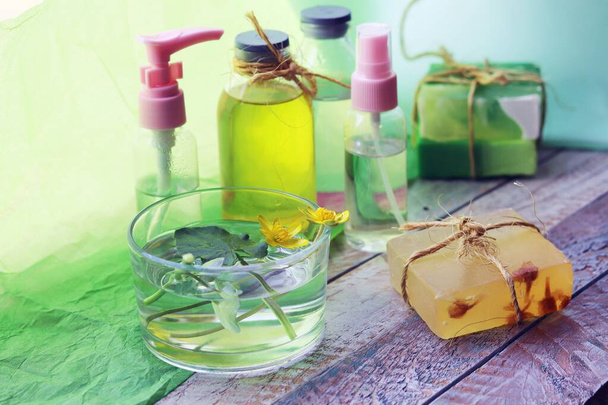 Természetes szappan, fertőtlenítőszer spray, olajok, tinktúrák és virágok a celandine egy fa ablakpárkányon, a koncepció a tisztaság, egészséges életmód, testápolás - Fotó, kép