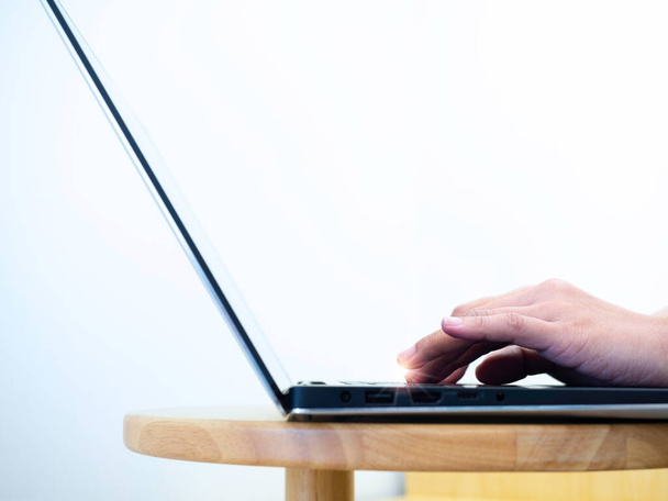 コピースペースが付いている白い背景の丸い木のテーブルのラップトップコンピュータのキーボードでタイプする女性の手の閉じる。オンラインビジネスの概念,技術を扱う,自宅から仕事,電子メールを書く. - 写真・画像
