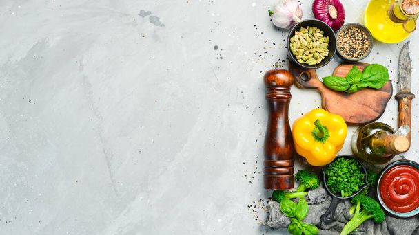 Cooking background. Composition of vegetables, spices, oil and kitchen utensils on a gray stone table. Top view. Free space for your text. - Foto, afbeelding