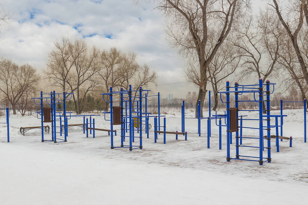 ストリートワークアウトのための空の雪のスポーツグラウンド。市内公園で運動設備を備えた無料の屋外ジム。公共公園で屋外ジムやフィットネス機器。スポーツの練習とアクティブな健康的なライフスタイル - 写真・画像