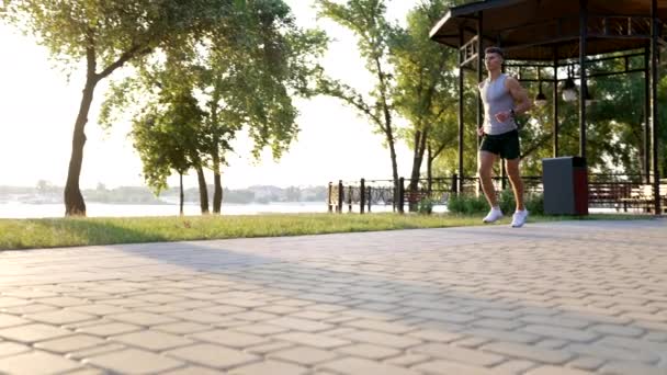 日当たりの良い公園の屋外で走るアクティブな男の朝の訓練、急いで - 映像、動画