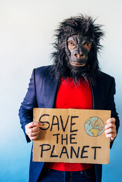 ゴリラのマスクの男は地球を救うと言うサインを示してる. - 写真・画像