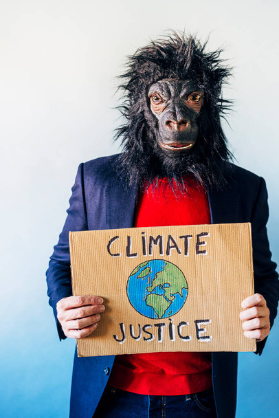 Homme avec masque de gorille montrant un signe qui dit JUSTICE CLIMATIQUE. - Photo, image