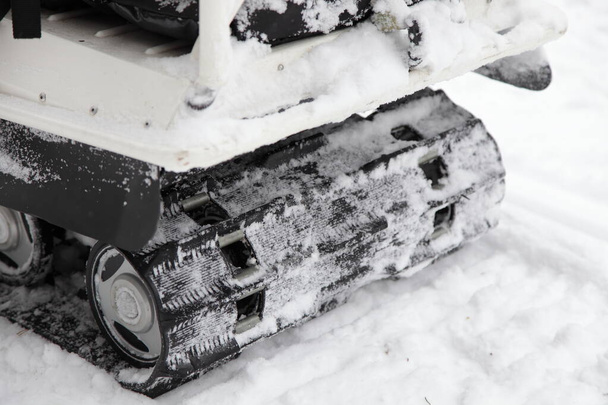 Russian utility snowmobile roller crawl drive gear suspension close up, crawler vehicle back view on snowy track background - Foto, Imagen