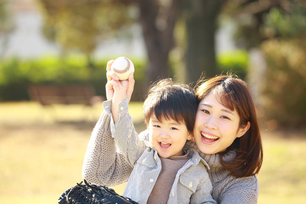 joven madre y adorable feliz pequeño hijo jugando juntos en parque - Foto, imagen