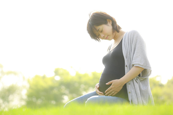 公園にいる若い美しいアジア系の妊婦は  - 写真・画像