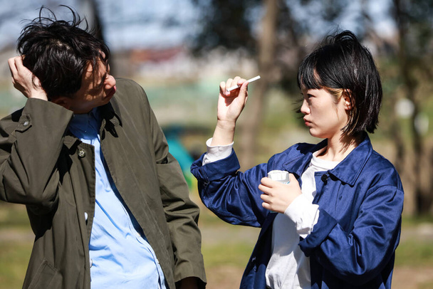 Asian man smoking cigarette near woman on the street - Valokuva, kuva