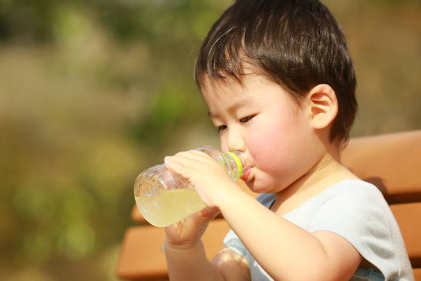 Küçük çocuk şişeden su içiyor.   - Fotoğraf, Görsel