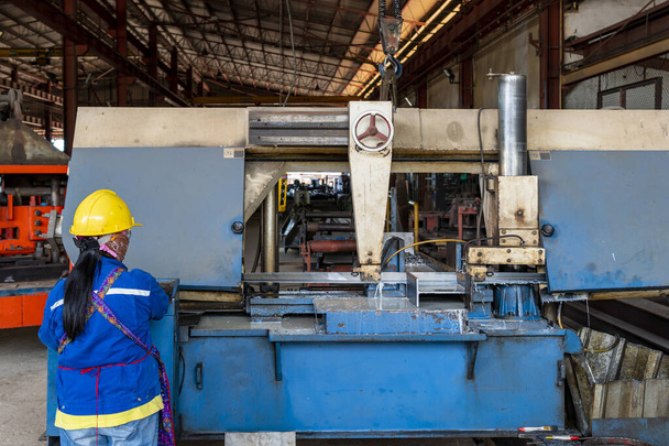 Arbeiter schneidet Stahl-H-Träger mit automatischer Metallbandsäge. - Foto, Bild
