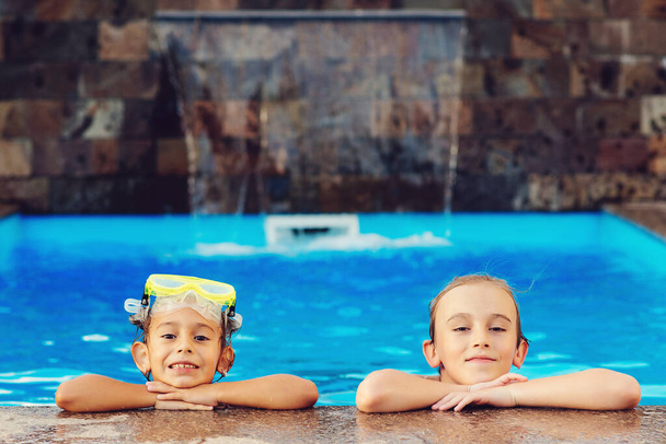 Amici che nuotano nella piscina all'aperto e si divertono insieme. Vacanza in famiglia e concetto di turismo. Bambini felici in piscina. Giochi d'acqua e divertimento acquatico per bambini. - Foto, immagini