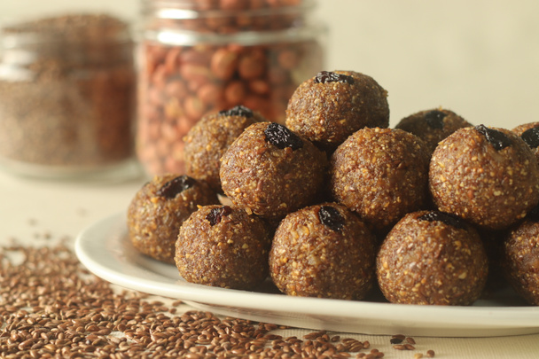 Flax seed peanut laddu. Indian sweet made with coarsely ground flax seeds and groundnuts with freshly grated coconut and jaggery, flavoured by cardamom. Shot with roasted flax seeds and peanuts beside - Photo, Image
