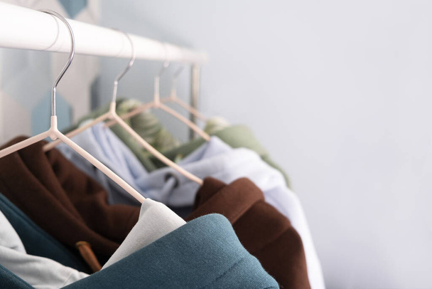 Row of multi-colored knitted hoodies, sports sweaters hanging on a hangers in an atelier or sportswear of Retail store close-up. pastel cold colors. - Foto, imagen