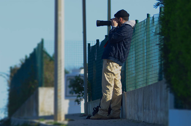 Ένας φωτογράφος που τραβάει φωτογραφίες από απόσταση με τηλεφακό - Φωτογραφία, εικόνα