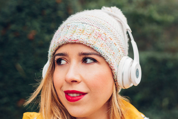 Portrét ženy, která poslouchá hudbu s bezdrátovými sluchátky, se spontánní tváří, autenticitou a přirozeností venku. - Fotografie, Obrázek