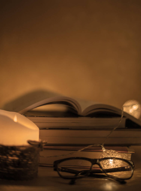 un libro aperto in cima ad altri libri in colonna con una candela che illumina - Fotografie, Obrázek