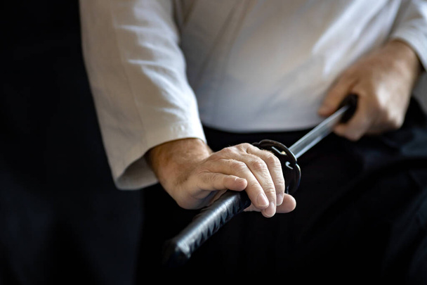 Боец боевых искусств в белом кимоно вытаскивает свой меч из ножен. Меч самурая - Фото, изображение
