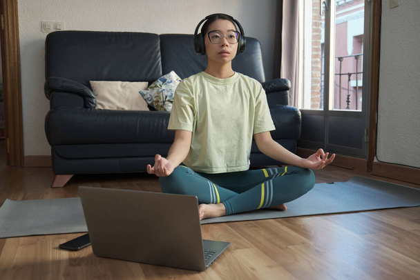 Young asian woman listening relaxing music and meditating doing the easy pose. - Photo, Image