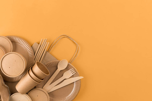 Eco-friendly tableware set. Kraft paper food packaging, paper containers and cups, drinking straws on orange background with copy space. Street food paper packaging concept. Ethical consumerism - Photo, Image