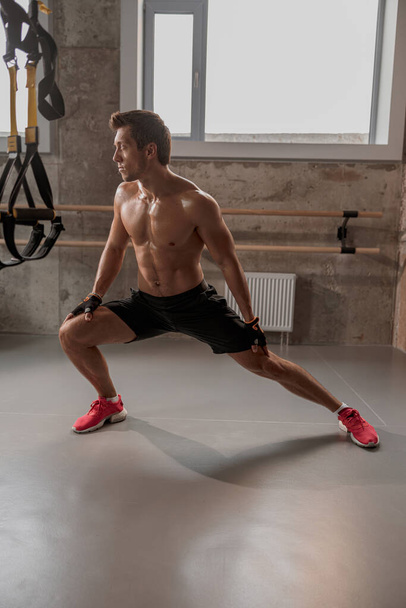 Shirtless athletic man doing lunge exercise at gym - Фото, изображение