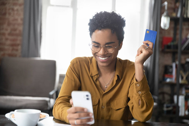 Happy millennial Black girl enjoying online shopping, using ecommerce app - Zdjęcie, obraz