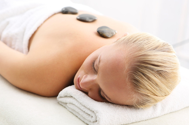 Hot stone massage, a woman in spa salon - Zdjęcie, obraz