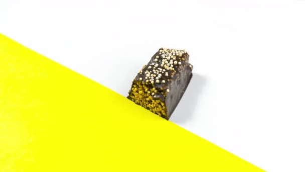 4k Fehér háttér sárga akcentussal, egy téglalap alakú csokoládé cukorka közelről jelenik meg, és fokozatosan eltűnik, ahogy eszik. Édes desszert koncepció. Állítsd le a mozgást. Másold a helyet. Lapos fektetés. - Felvétel, videó