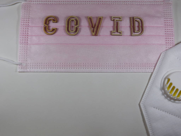 Het woord covid variant omicron in houten letters op het gezichtsmasker - Foto, afbeelding