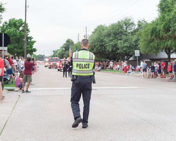 Police officer walking along street at public July 4 parade event near Dallas, Texas, America. Law enforcement and security guard at live festival event. - Photo, Image