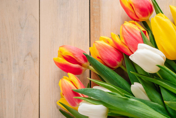 Gele tulpen op een lichte houten achtergrond. Voorjaars- en vakantieconcept. - Foto, afbeelding