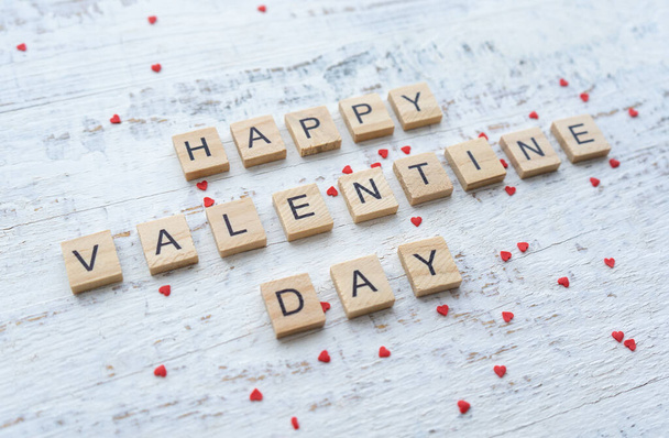 Boldog Valentin-napi üdvözlőlapot. Fa betűk a fehér háttér kis szétszórt piros szív.  - Fotó, kép