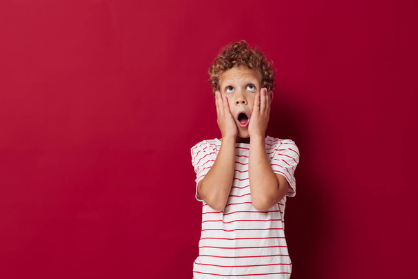 Веселий хлопчик в повсякденному одязі позує емоції червоний фон
 - Фото, зображення
