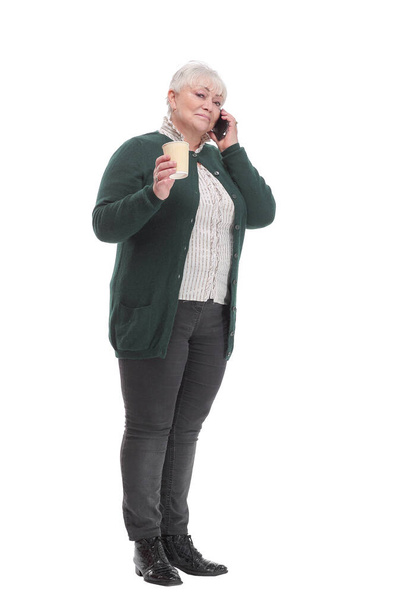 Happy mature woman with coffee cup talking on mobile phone and laughing. - Foto, afbeelding