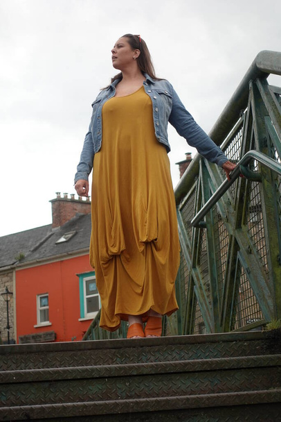 Pani stojąca na moście, aby podziwiać widok na wioskę Killaloe w Irlandii - Zdjęcie, obraz