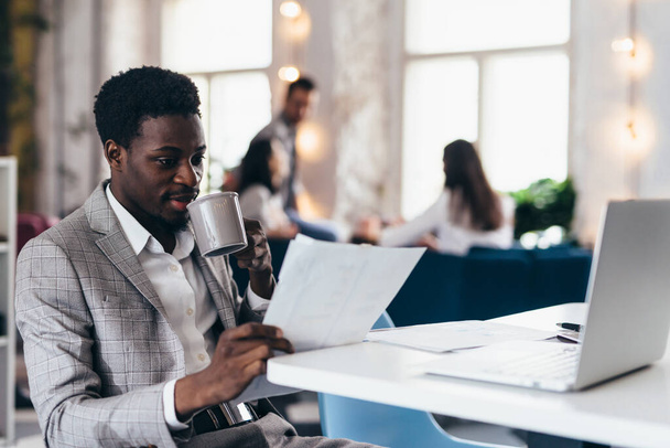 Fiatal fekete férfi használja laptop az irodában. - Fotó, kép