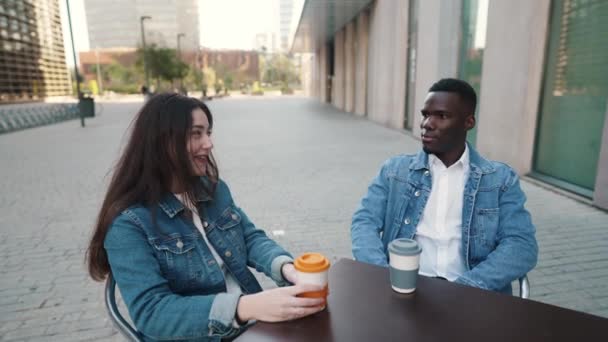 Iloinen monikansallinen pari juo kahvia kaupungissa - Materiaali, video