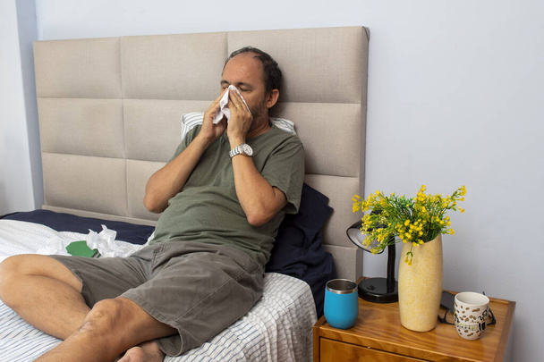Senior sitting on the bed in the room with the flu and several papers because of the sneezing - Fotoğraf, Görsel