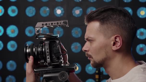 Videógrafo masculino europeo instala una cámara de vídeo para grabar en el estudio. - Imágenes, Vídeo