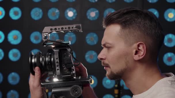 ヨーロッパの男性ビデオカメラマンは、スタジオで撮影するビデオカメラを設定します. - 映像、動画
