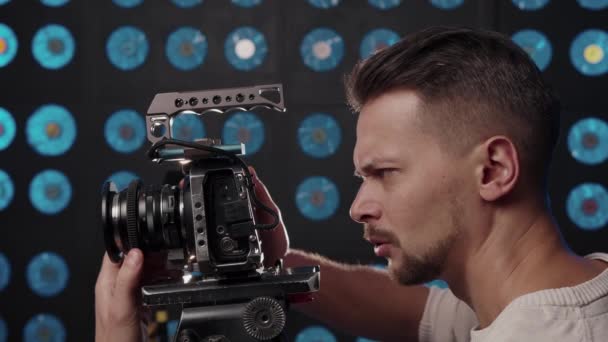 Videógrafo masculino europeo instala una cámara de vídeo para grabar en el estudio. - Metraje, vídeo