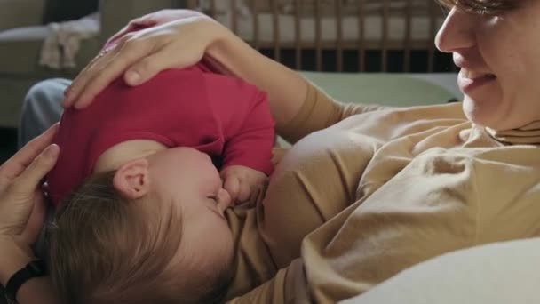 Video met een moeder streelt de baby als hij probeert in slaap te vallen in haar armen. Babyverzorging. - Video