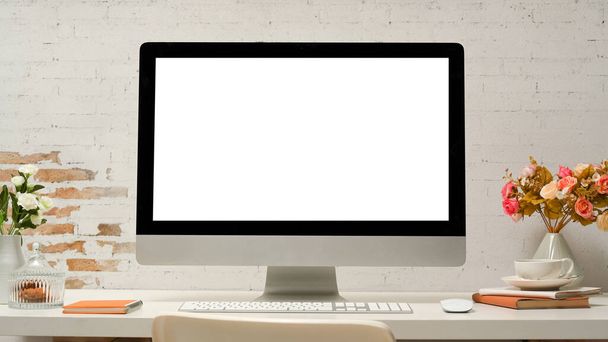 Escritorio de oficina moderno con la pantalla blanca del ordenador de escritorio de la PC, suministros de oficina, decoración en la mesa sobre la pared de ladrillo blanco. - Foto, Imagen