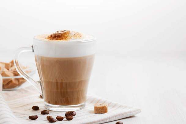Latte coffee poured in layers with froth and a crispy chocolate top on a light kitchen table, copy space - Foto, Bild