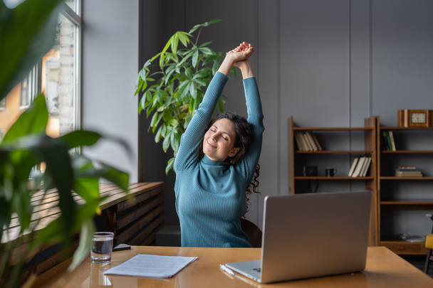 Glückliche Geschäftsfrau dehnt sich am Arbeitsplatz, Mitarbeiterin ruht sich vom Computerbildschirm aus - Foto, Bild
