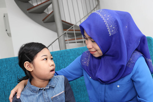 Południowo-wschodniej Azji Malajski szczególna potrzeba medyczny ADHD Autyzm syndrom matka córka siedzieć na niebieskiej kanapie talk show smart phone - Zdjęcie, obraz