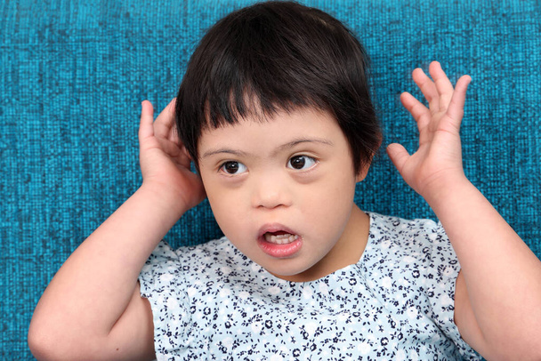 Südostasiatisches Kind Mädchen mit besonderen Bedürfnissen medizinische Down-Adhd-Autismus-Syndrom glücklich Lächeln Emotion Ausdruck blau Farbe Sofa - Foto, Bild
